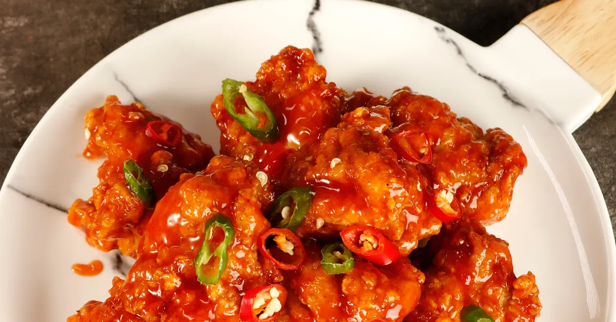 A plate of glossy Korean fried chicken with a fiery red glaze